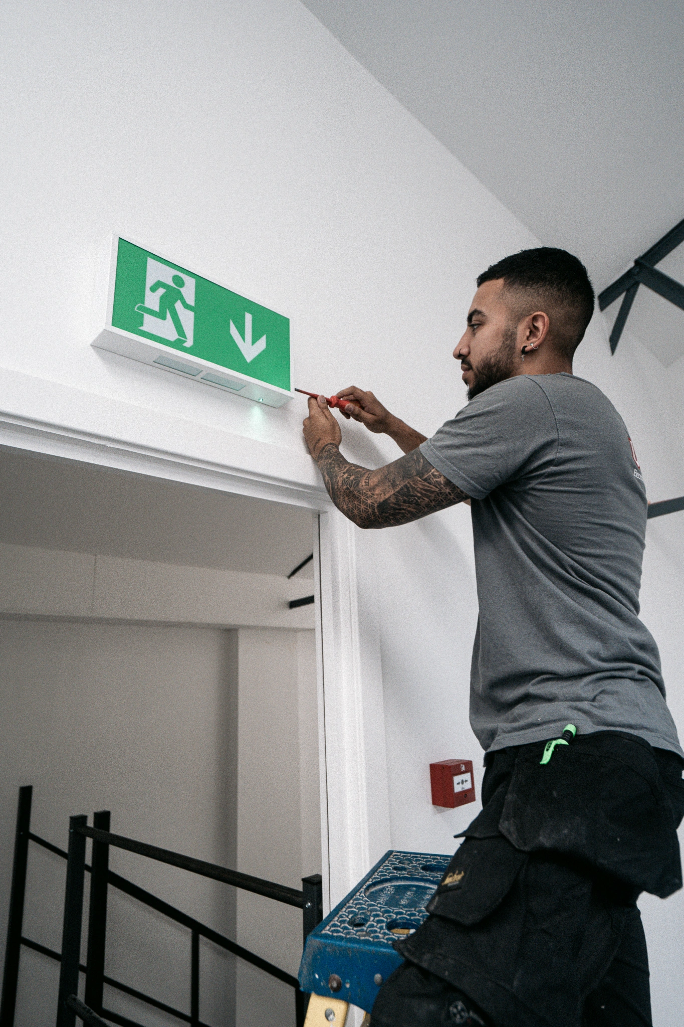 A ubitec electrician installing a emergency exit sign